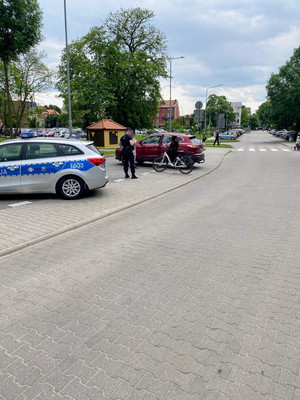 Patrol, policjant, radiowóz, pojazd osobowy oraz rower