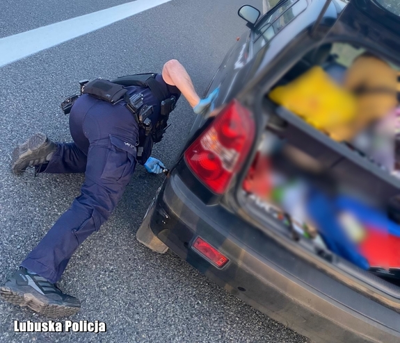 policjant przy aucie wymienia koło