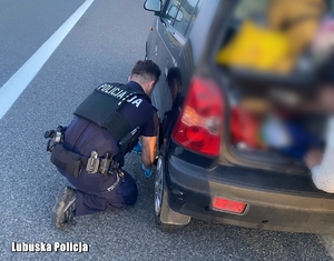 policjant przy aucie wymienia koło