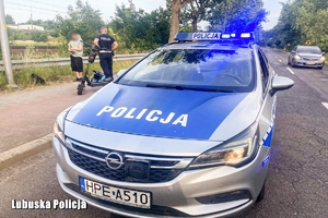 Radiowóz, ulica, chodnik, policjant, cywil i hulajnoga