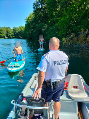 policjant na łodzi rozmawia z ludźmi na supach