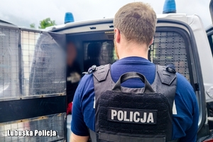 policjant przed radiowozem, w środku zatrzymany