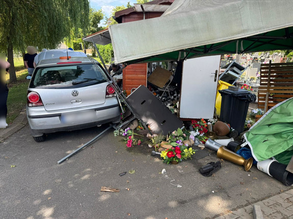 pojazd i uszkodzony kiosk na cmentarzu