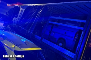 Policjanci, radiowozy, ciężarówka z busami na pace