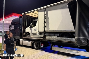 Policjanci, radiowozy, ciężarówka z busami na pace