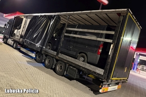 Policjanci, radiowozy, ciężarówka z busami na pace