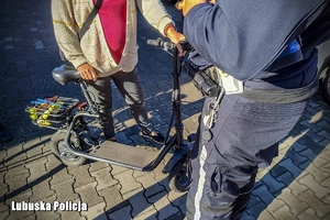 Policjant rozmawia z osobami na hulajnogach