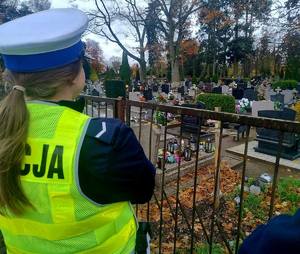 Radiowóz na tle cmentarza oraz policjantka na tle cmentarza