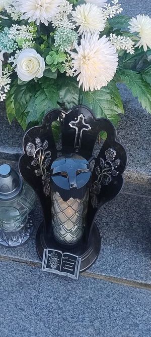 Policjant przy radiowozie ze zniczem, znicz przy nagrobku