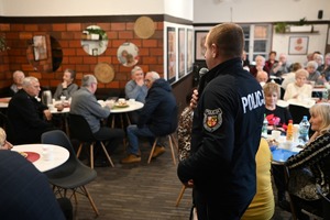 Policjant rozmawia z seniorami.