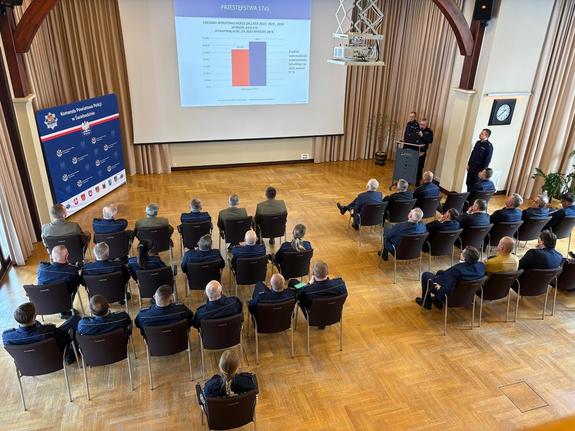 Zdjęcia z odprawy, sala, wyświetlona prezentacja, przemówienia i mundurowi oraz goście na krzesłach