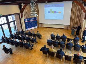 Zdjęcia z odprawy, sala, wyświetlona prezentacja, przemówienia i mundurowi oraz goście na krzesłach