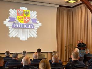 Zdjęcia z odprawy, sala, wyświetlona prezentacja, przemówienia i mundurowi oraz goście na krzesłach