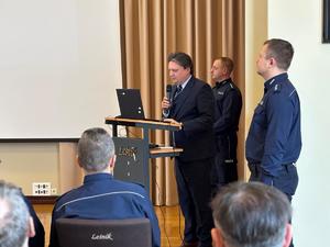 Zdjęcia z odprawy, sala, wyświetlona prezentacja, przemówienia i mundurowi oraz goście na krzesłach