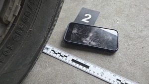 rozbity telefon na drodze, obok koło pojazdu