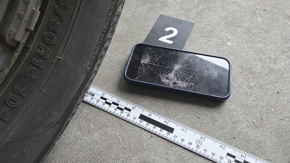 rozbity telefon na drodze, obok koło pojazdu