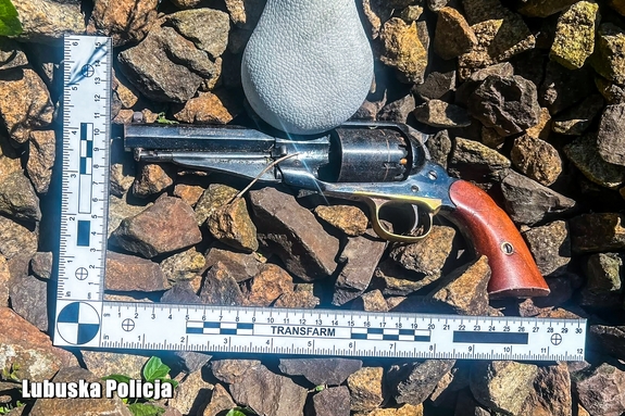 Policjanci prowadzą mężczyznę, broń czarnoprochowa, przestrzelina w szybie